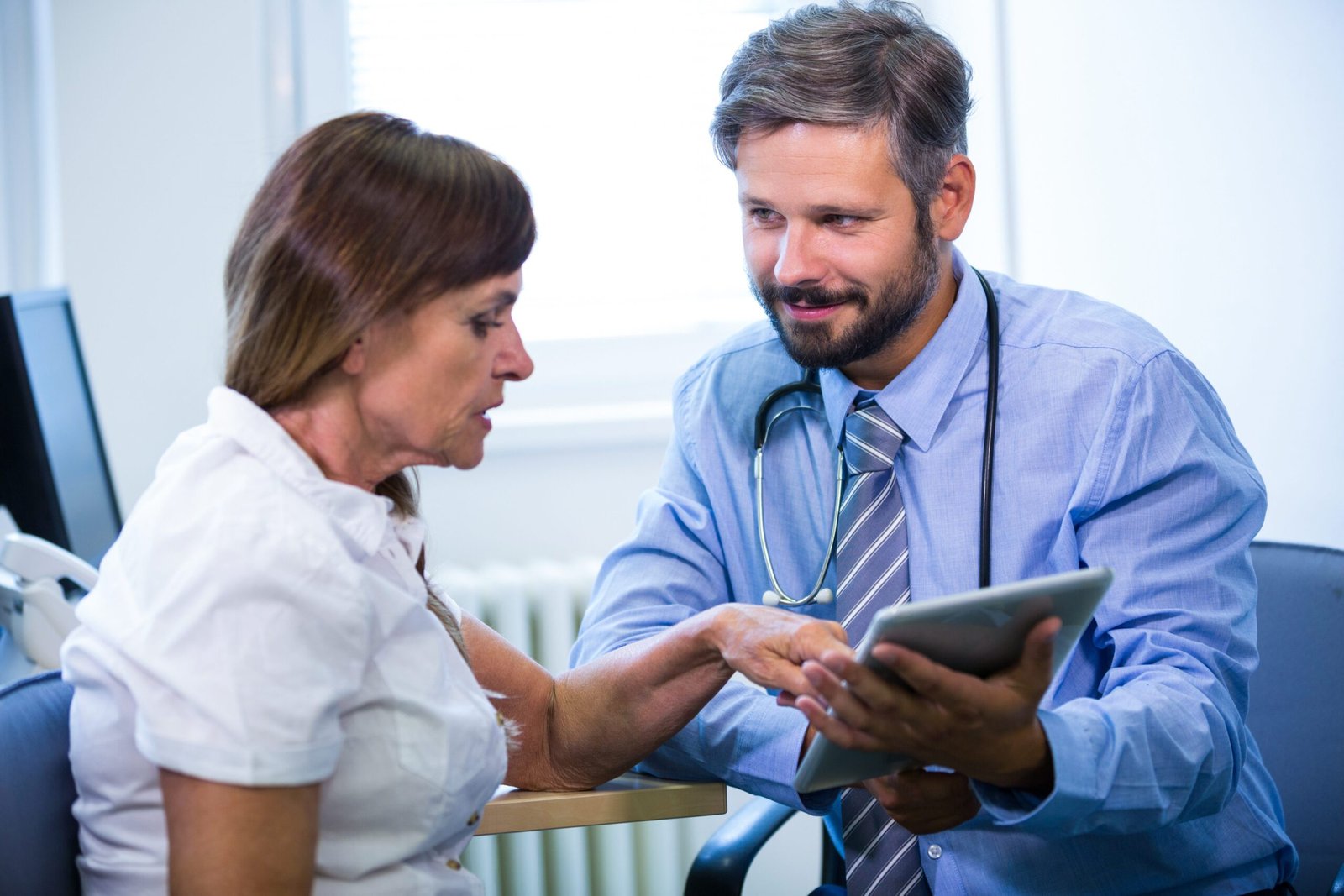 Male doctor discussing with patient over digital tablet Male doctor discussing with patient over digital tablet at the hospital